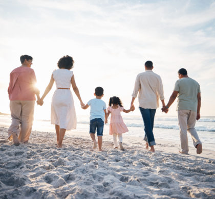 Walking, holding hands and back of big family at the beach for travel, vacation and adventure in nature. Love, freedom and rear view of children with parents and grandparent at sea for ocean journey.