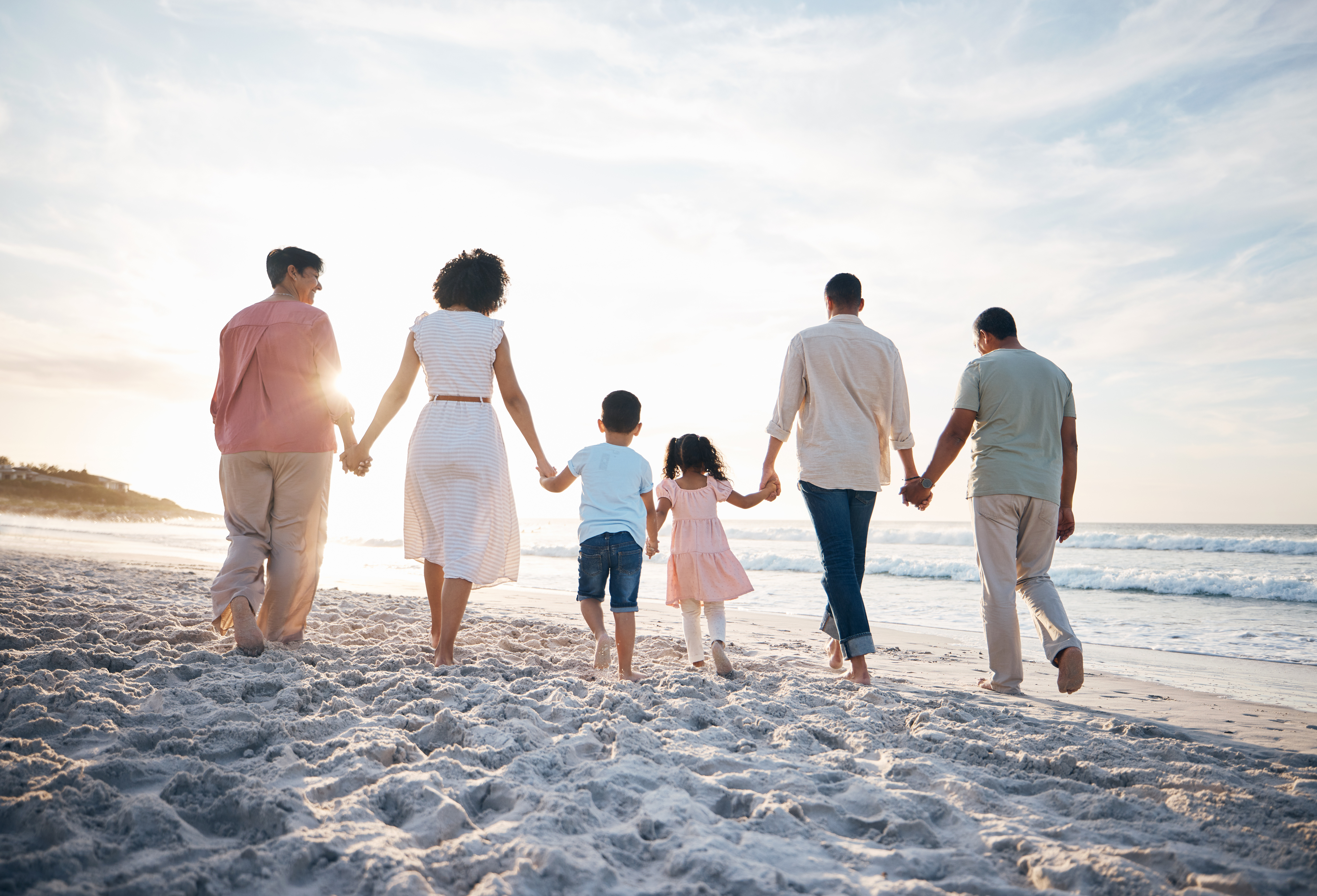 Walking, holding hands and back of big family at the beach for travel, vacation and adventure in nature. Love, freedom and rear view of children with parents and grandparent at sea for ocean journey.